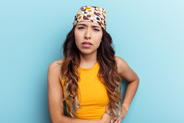 Young mexican woman isolated on blue background having a liver pain, stomach ache.