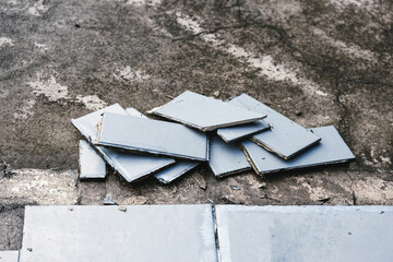 blue outdoor tiles getting ripped up to reveal concrete paving underneath, concept of demolition or...