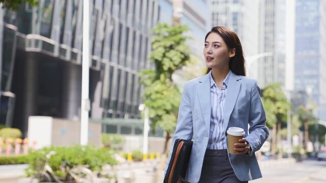 successful young asian business woman walking on downtown street in modern city