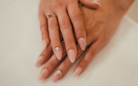Wedding manicure. French classic manicure on long sharp nails with crystals close up on a white background