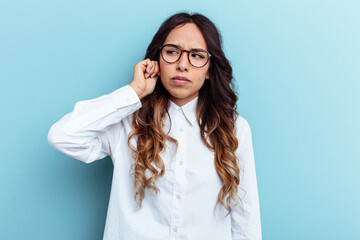 Young mexican woman isolated on blue background covering ears with fingers, stressed and desperate by a loudly ambient.
