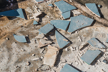 blue outdoor tiles getting ripped up to reveal concrete paving underneath, concept of demolition or...