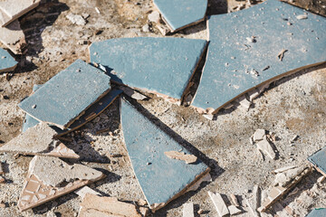 blue outdoor tiles getting ripped up to reveal concrete paving underneath, concept of demolition or renovation
