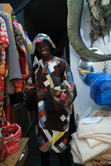 Black man wearing an african item of clothing, smiling and looking at camera. African tailor in his sewing workshop.