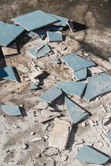 blue outdoor tiles getting ripped up to reveal concrete paving underneath, concept of demolition or renovation