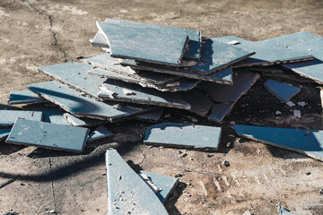 blue outdoor tiles getting ripped up to reveal concrete paving underneath, concept of demolition or...