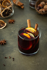Mulled wine with lime and orange slices, cinnamon and cloves, hot winter drink in a glass mug