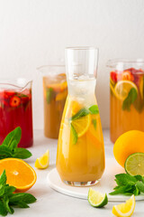 Jugs of fresh refreshing fruit drinks with fruit wedges, summer cold juices with ice