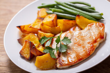 plate of grilled turkey with baked potatoes and green beans