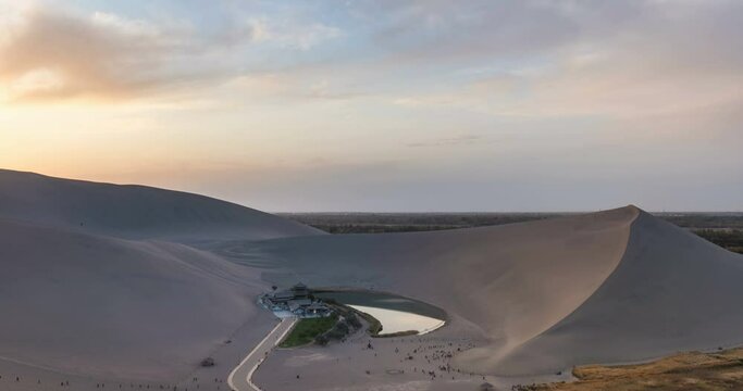 time lapse of the Mingsha Mountain and Crescent Spring at dusk, ​Dunhuang city, Gansu province, a famous tourist attraction in China.