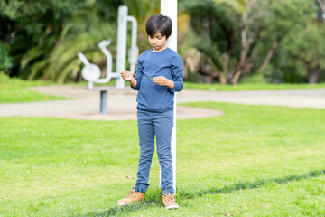 Portrait of lonely child looking sad. Young boy standing at park holding blade of grass. Shot in natural light. 