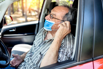 Portrait of senior driver wearing protective medical mask. Old man with facial mask due to...