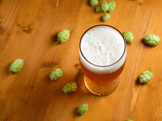 Light hopped beer on a wooden table, fresh green wild hops, the concept of craft beer