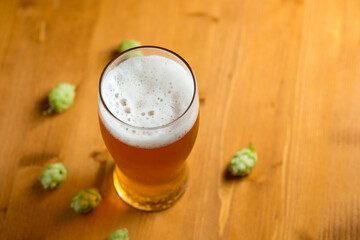 Light hopped beer on a wooden table, fresh green wild hops, the concept of craft beer