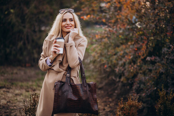 Elderly woman drinking coffee outside the autumn park