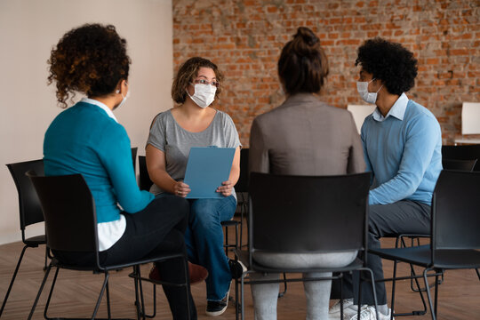 diverse business workgroup collaborating and discussing at meeting with face mask.