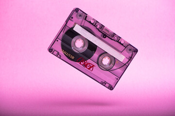 falling vintage audio cassette on pink background.