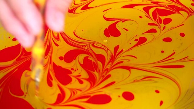Abstract marbling ebru colorful yellow background with red flower patterns.