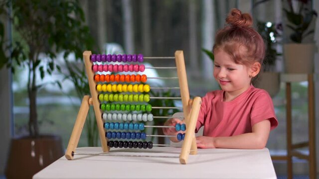little cute girl play bills home. child is busy play and learn mathematics. childhood and entertainment. Happy family preschool girl at table with multicolored rainbow MULA ikea toy. Toddler Education