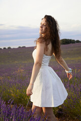 Fototapeta na wymiar Photos of a young woman in the lavender fields of Brihuega, in Spain. She is spinning around in a white dress blowing in the wind. Lifestyle. Beauty