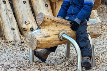 A boy is sitting on a wooden projectile for physical exercises