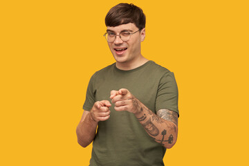 Indoor shot of young male student, keeps mouth widely opened, indicates with both point fingers...