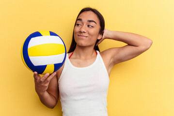 Young mixed race woman playing volleyball on the beach isolated on yellow background touching back of head, thinking and making a choice.