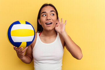 Young mixed race woman playing volleyball on the beach isolated on yellow background trying to...