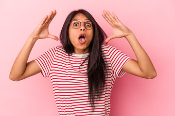 Young latin woman isolated on pink background celebrating a victory or success, he is surprised and shocked.