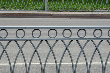 A fragment of a metal fence of the roadway of a city street
