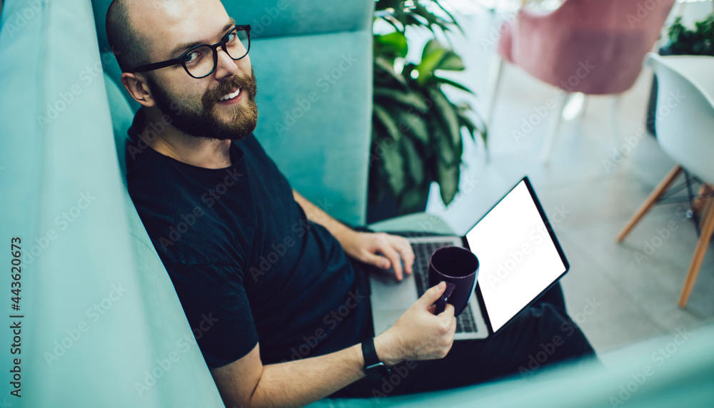 Poster portrait of happy graphic designer with coffee using mockup laptop with copy space area for your web