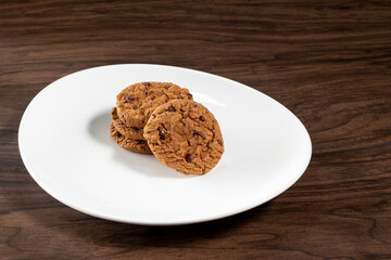 Plate of freshly baked chocolate chip cookies. Wooden background, selective focus
