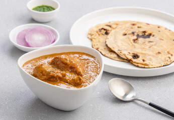butter chicken gravy served in a white bowl with flatbread roti or naan