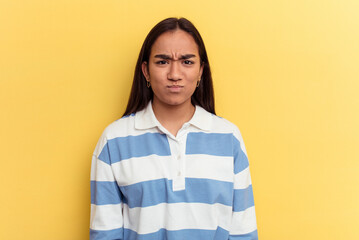 Young mixed race woman isolated on yellow background blows cheeks, has tired expression. Facial...