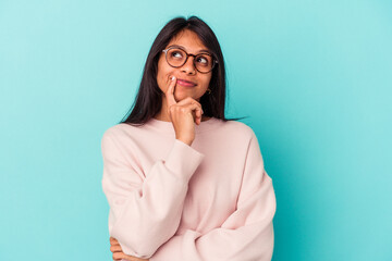 Young latin woman isolated on blue background contemplating, planning a strategy, thinking about...