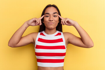Young mixed race woman isolated on yellow background focused on a task, keeping forefingers pointing head.