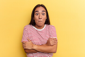 Young mixed race woman isolated on yellow background shrugs shoulders and open eyes confused.