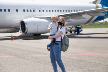 Happy family on the background of the plane. Woman and child travel together