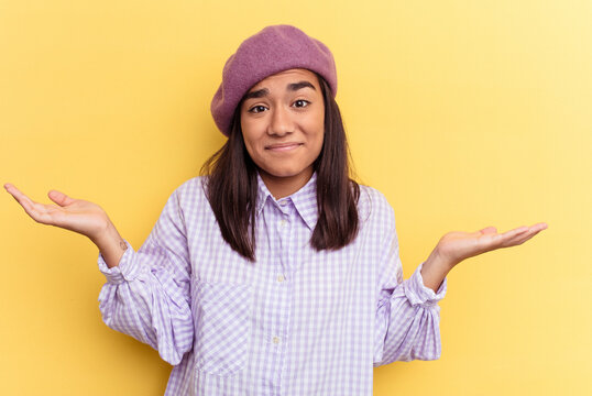 Young mixed race woman isolated on yellow background doubting and shrugging shoulders in questioning gesture.