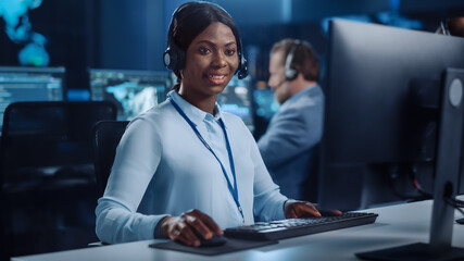 Joyful Beautiful Technical Customer Support Specialist is Talking on a Headset while Working on a...