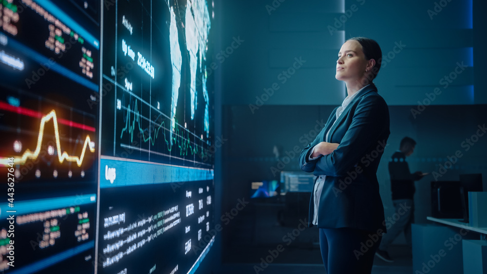 Poster Young Female Computer Science Engineer Looking at Big Screen Display Showing Global Map with Data Points. Telecommunications Technology Company System Control and Monitoring Room with Servers.
