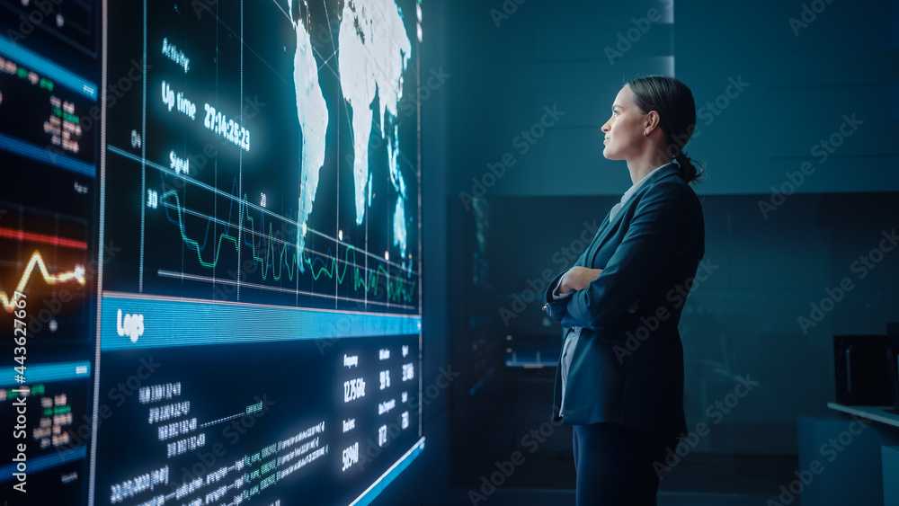 Poster Young Female Computer Science Engineer Looking at Big Screen Display Showing Global Map with Data Points. Telecommunications Technology Company System Control and Monitoring Room with Servers.