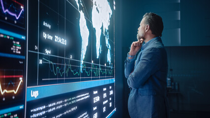 Senior Computer Science Engineer Looking at Big Screen Display Showing Global Map with Data Points....