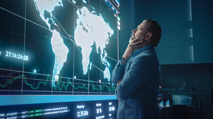 Senior Computer Science Engineer Looking at Big Screen Display Showing Global Map with Data Points. Telecommunications Technology Company System Control and Monitoring Room with Servers.