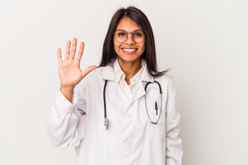 Young doctor latin woman isolated on white background smiling cheerful showing number five with...