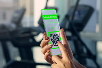 Vaccinated person using futuristic mobile phone application to show proof of immunity at the gym .