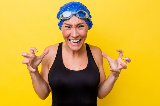 Young australian swimmer woman isolated on yellow background screaming with rage.