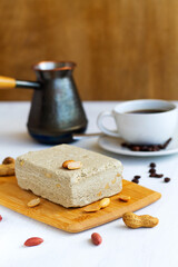 national traditional sweetness of Turkish and arabic halva with cup of coffee on the white table. halwa from sunflower seeds with peanut on the wood cutting board. tasty dessert. vertical. copy space