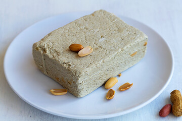 piece of halwa prepared from sunflower seeds with peanut on the white plate. national traditional sweetness of Turkish halva on the table