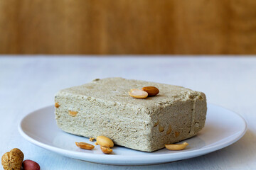 piece of sweet halwa prepared from sunflower seeds with peanut on the white plate. national traditional sweetness of Turkish halva on the table with copy space